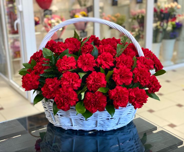 Червоні гвоздики в білому кошику 