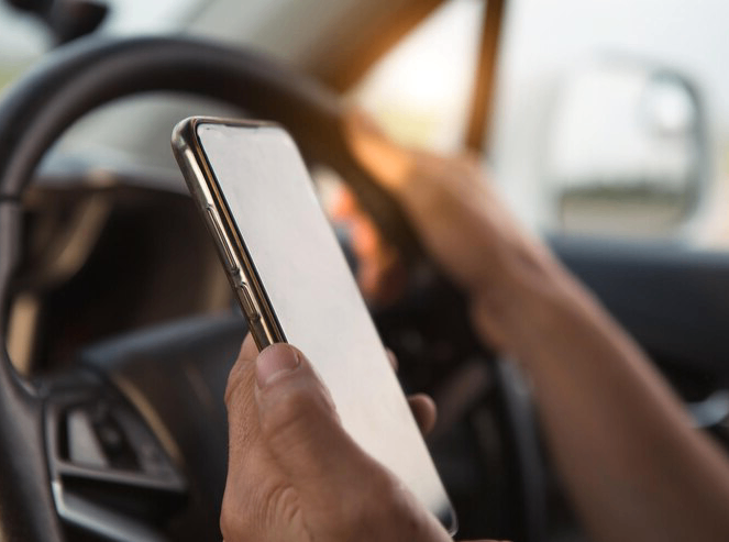 the-driver-s-hand-behind-the-wheel-holds-a-smartphone-navigator-satellite-navigation-communication-in-the-car-road-safety-speakerphone_292419-3095