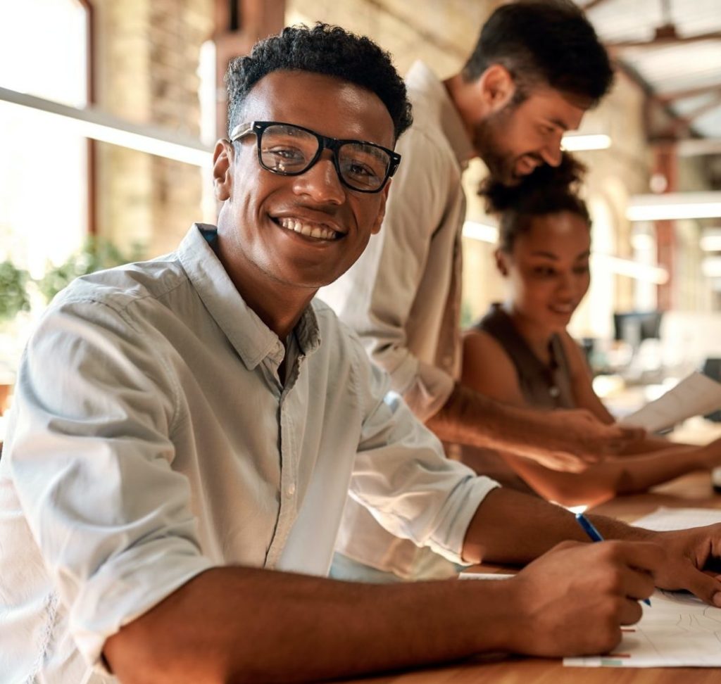 young-and-cheerful-afro-american-man-in-eyeglasses-looking-at-camera-with-smile-while-working-with-e1655104993151-1024x972