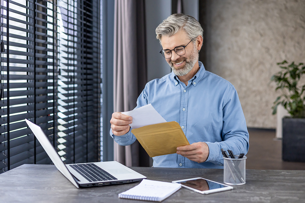 smiling-senior-man-sitting-at-home-at-work-desk-wi-2025-03-25-22-39-20-utc