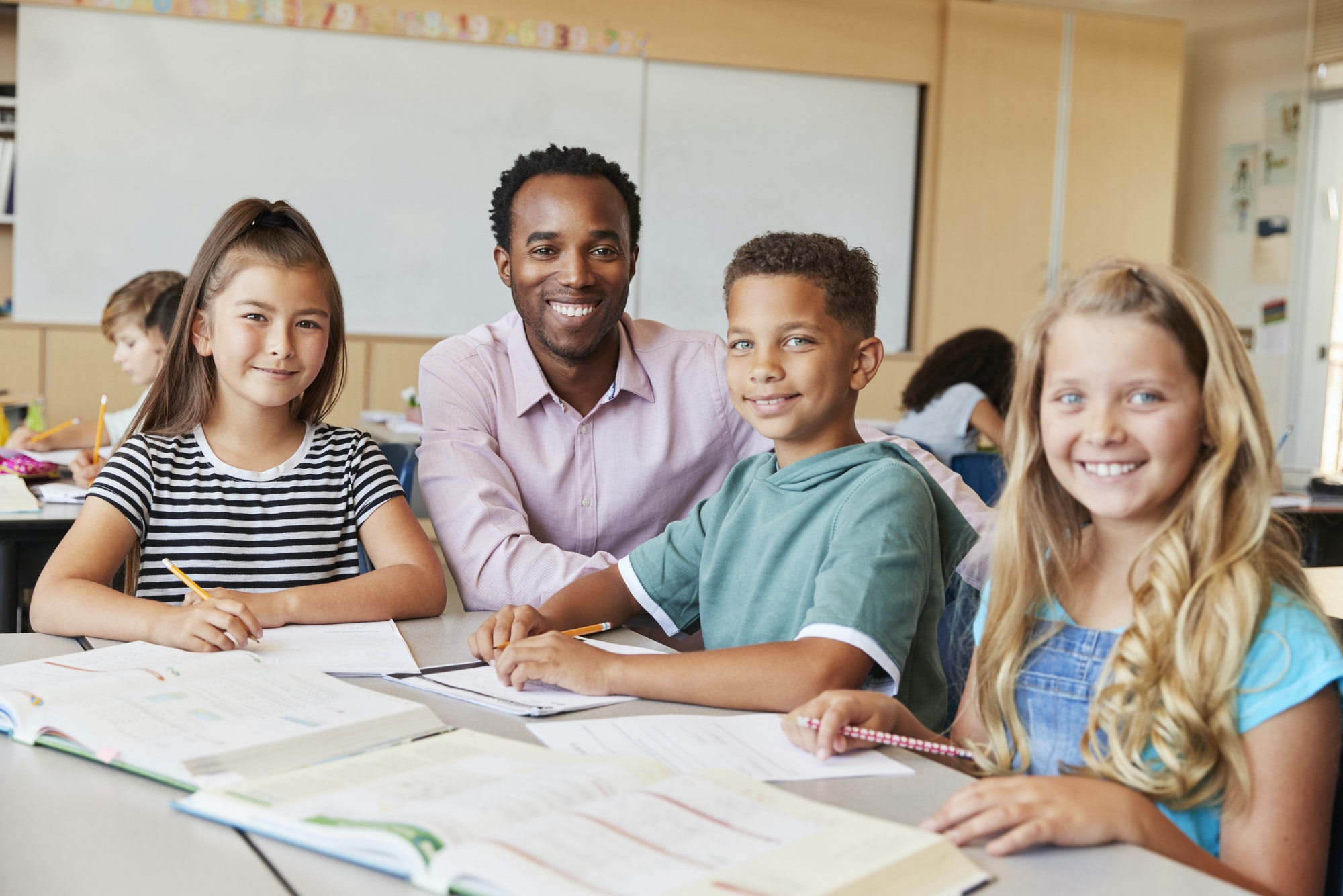 male-school-teacher-and-kids-in-class-smiling-to-camera