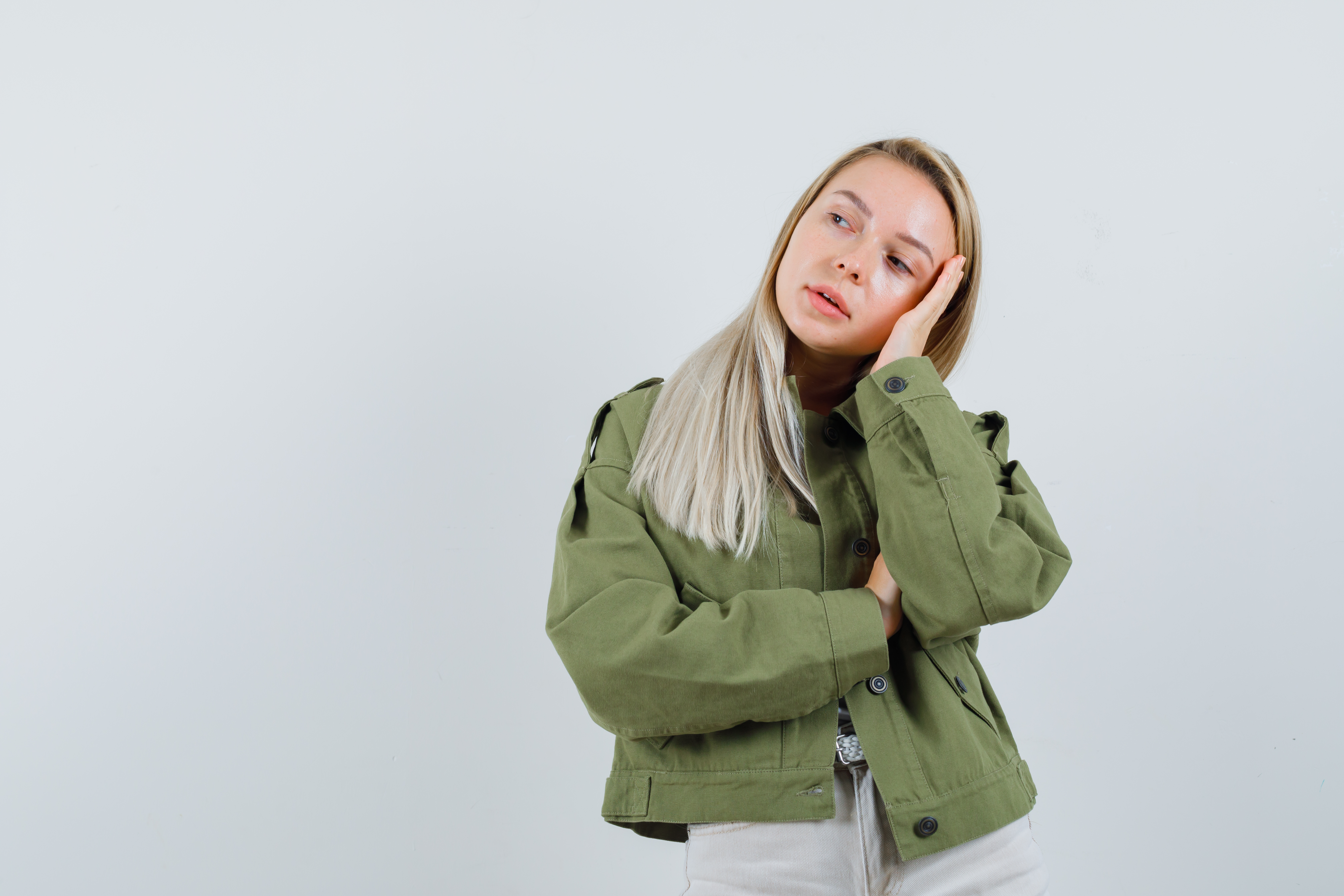 blonde-lady-leaning-head-palm-jacket-pants-looking-pensive-front-view
