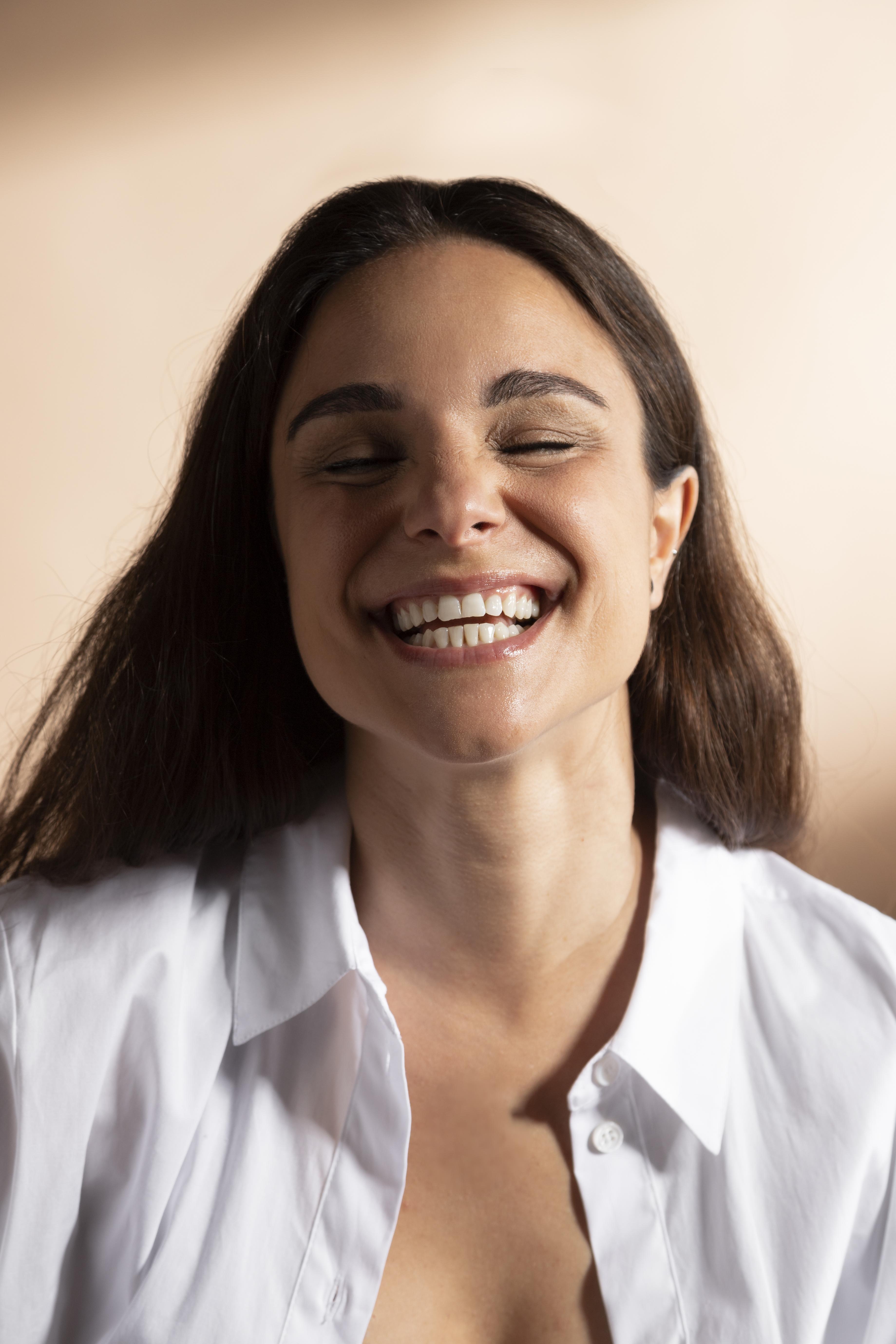 retrato-de-uma-mulher-sorridente-posando-com-uma-camisa-branca