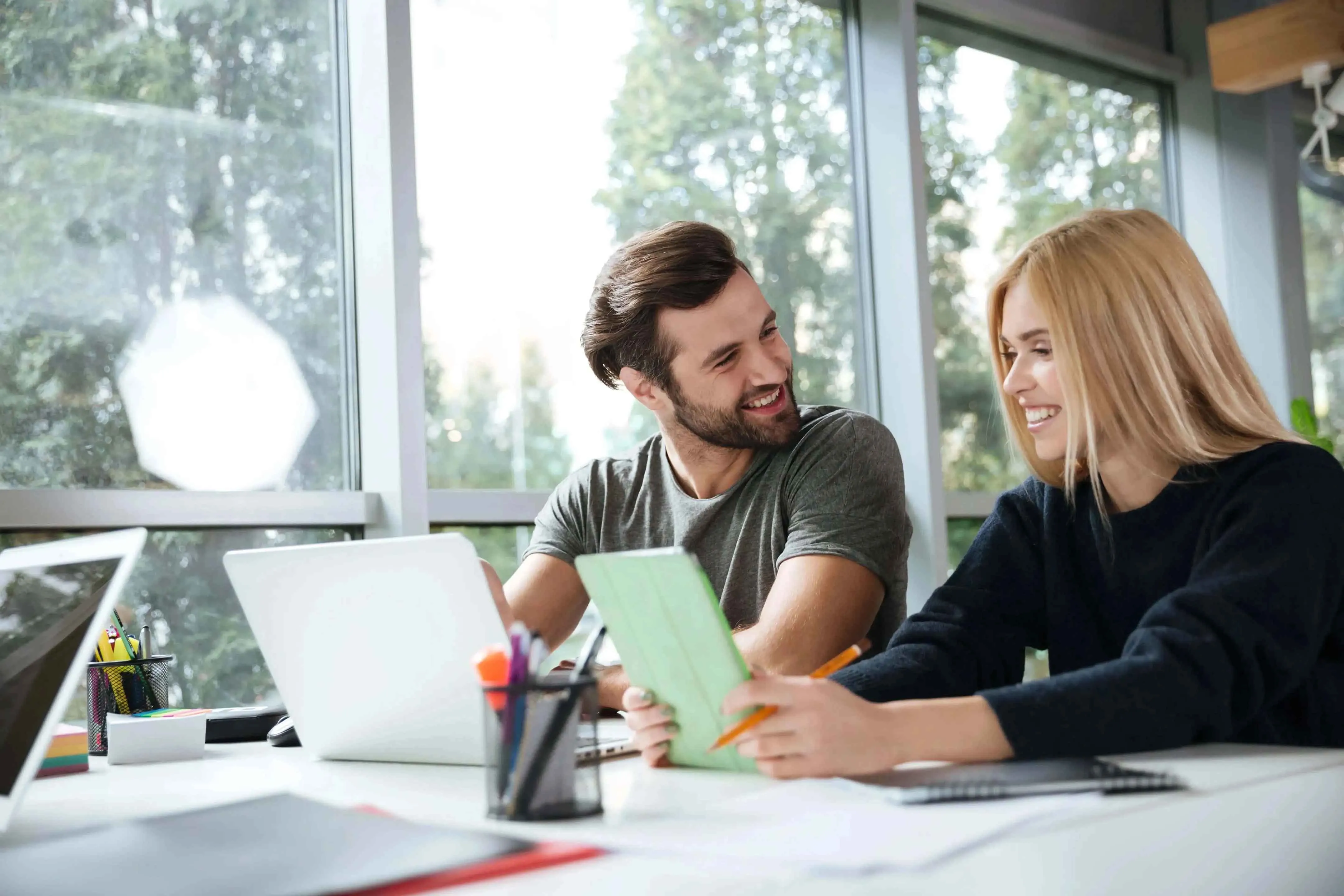 smiling-young-colleagues-sitting-office-coworking